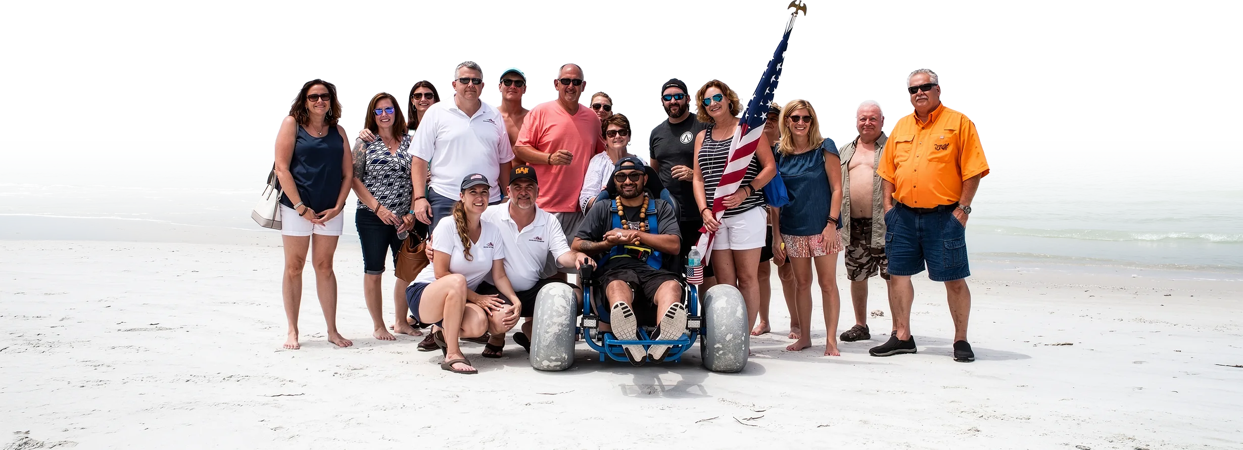 Volunteers and veterans gathered on the beach around a beach wheelchair