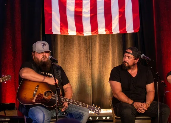 Songwriters for Vets performers on stage with an American flag