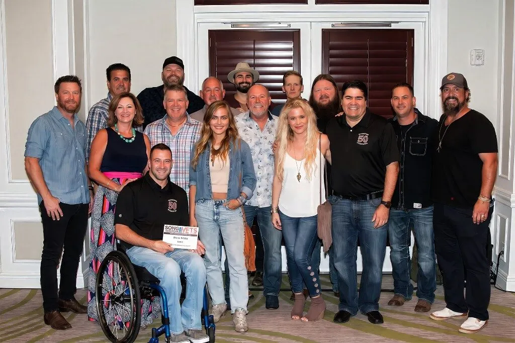 Songwriters for Vets group with a Song Vets 50 sign